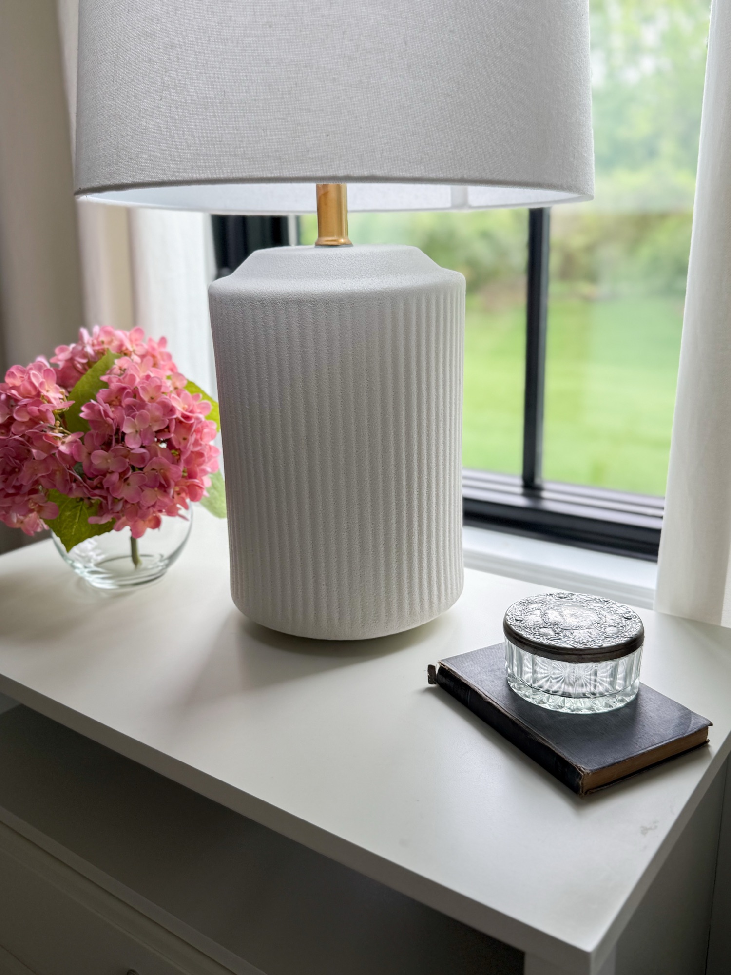 night stand styled with ceramic white lamp, vintage jewelry dish and vibrant pink hydrangeas